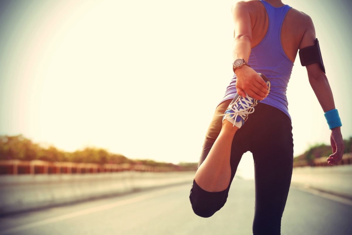 young ftiness woman runner stretching legs before run