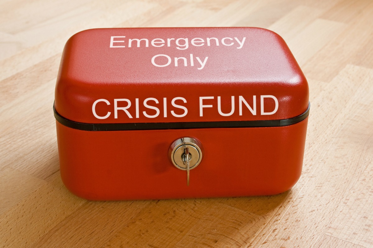 Closed red cash tin marked Crisis Fund - Emergency Only